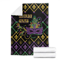 Folded black geometric Mardi Gras blanket with purple mask and 'MARDI GRAS' text, gold trim.