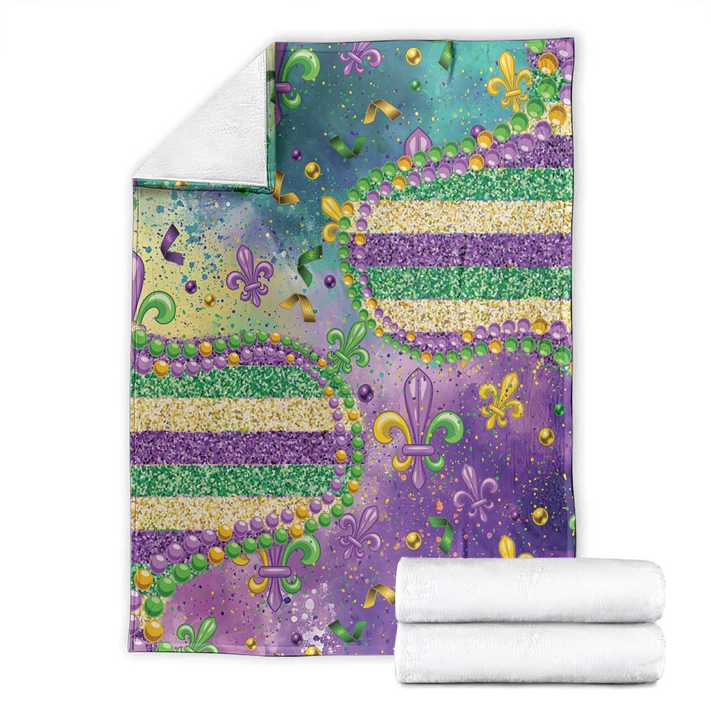 Folded Mardi Gras blanket in teal and purple with fleur-de-lis glitter bead pattern and gold stars