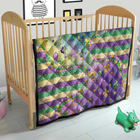 Fleur-de-lis quilt on a crib with purple, teal, and gold stripes and glitter bead accents