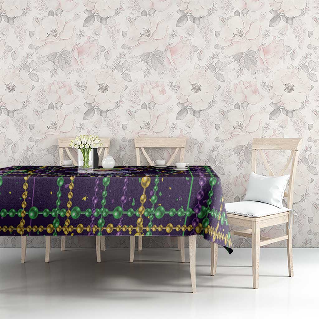 Mardi Gras tablecloth on long table, purple and green bead garlands with gold trim