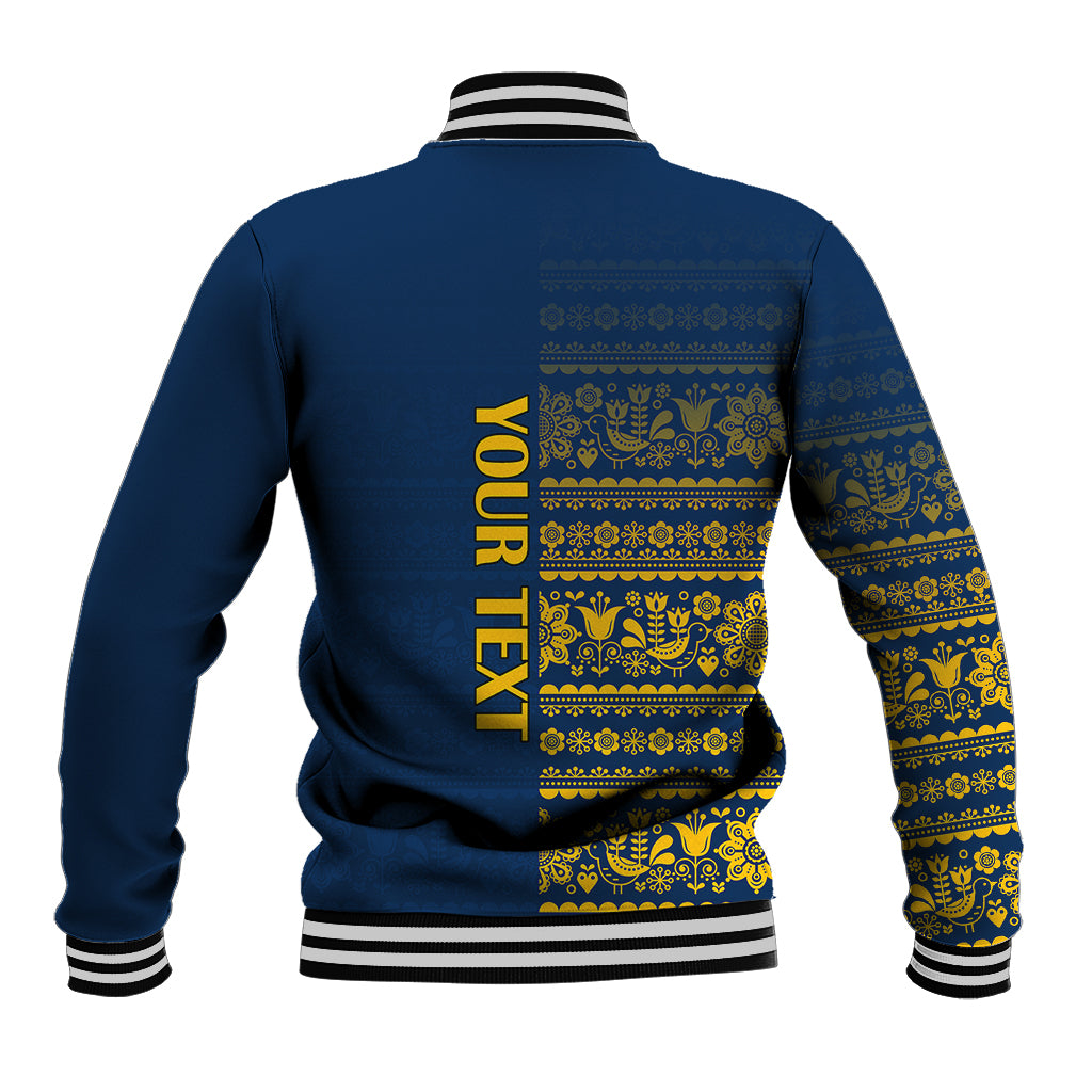Blue varsity baseball jacket with yellow folk pattern and vertical back text, striped ribbed cuffs