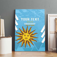 Blue canvas wall art displayed on wood shelf with Uruguay sun logo and “YOUR TEXT”.