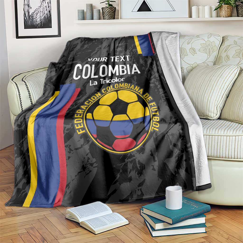 Black Colombia football blanket draped over couch, with emblem and tricolor stripe accents