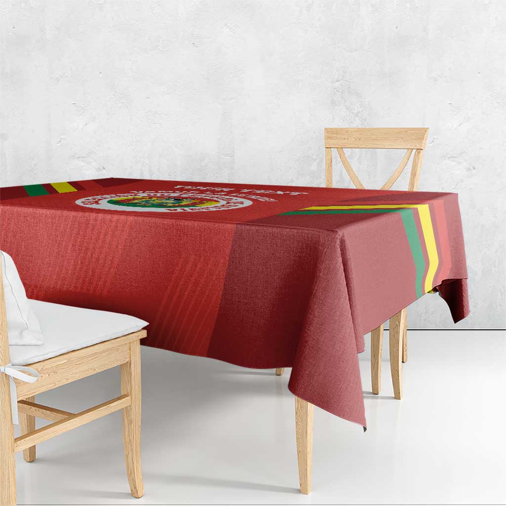 Red football tablecloth draped over a wooden table, with multicolor diagonal stripe edges