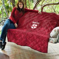 Red quilt with diamond stitching, custom text, and England crest emblem draped on couch