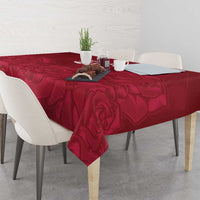 Red rose-pattern tablecloth covering a dining table with hanging corners