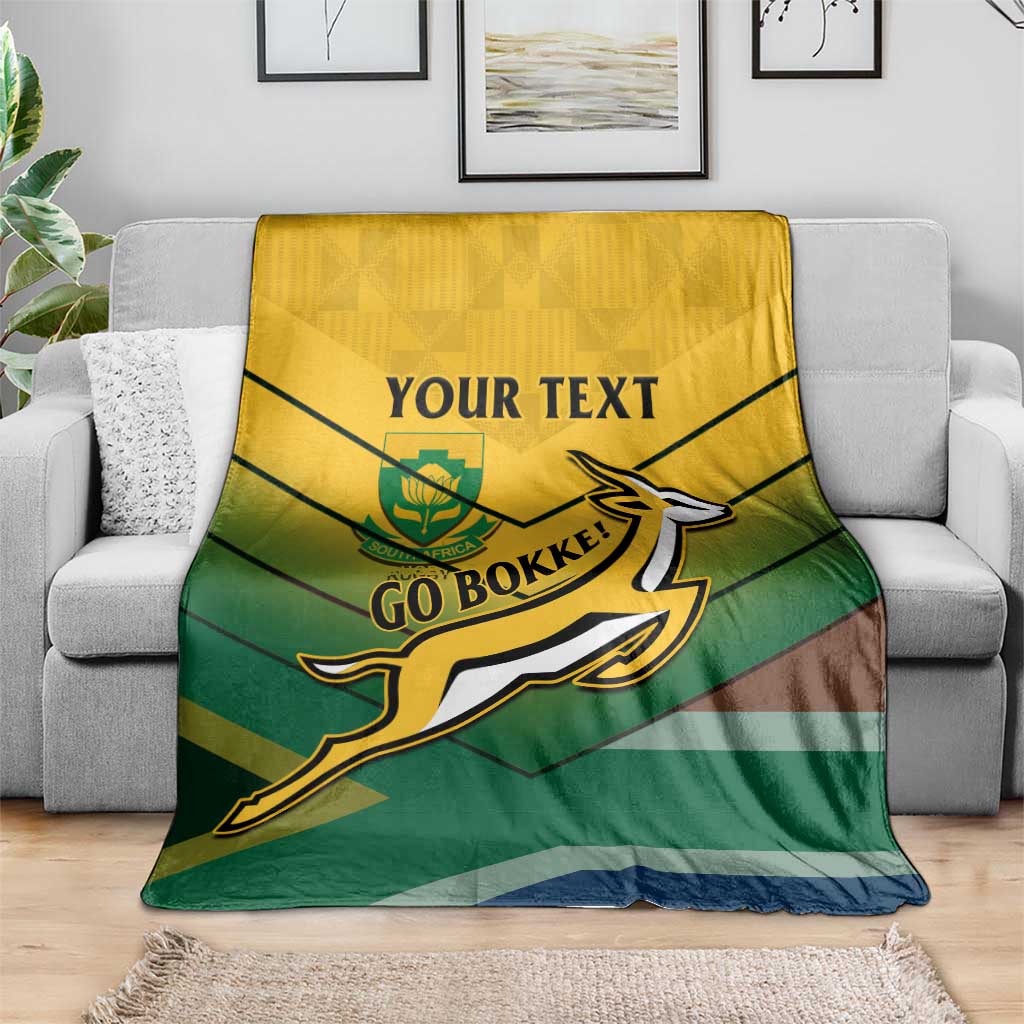 South Africa rugby blanket draped on gray couch, yellow-green stripes and Go Bokke crest