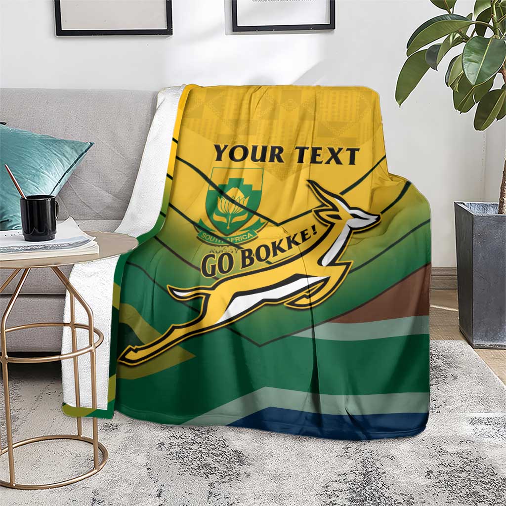 South Africa rugby blanket over gray chair, green-and-brown stripes with Go Bokke logo