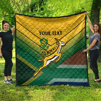 Custom rugby quilt spread outdoors in green, yellow, and blue with rugby player emblem and “YOUR TEXT”