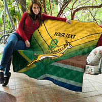 Custom rugby quilt draped across couch in green-yellow-blue-brown with rugby player emblem