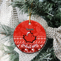 Red round Canada ceramic Christmas ornament with maple leaf and Noel text hanging on a tree