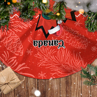 Red Christmas tree skirt with large black maple leaf emblem and white bow