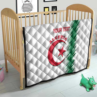 White quilt with Algeria logo and green diagonal stripe, red “YOUR TEXT” on crib