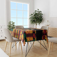 Black tablecloth with multicolor Adinkra symbols draped over dining table