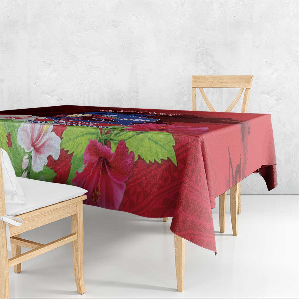 Red tablecloth with large hibiscus flowers and green leaves, hanging over table edge