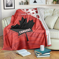 Red blanket with maple leaves and CANUCKS logo, hanging over couch with books