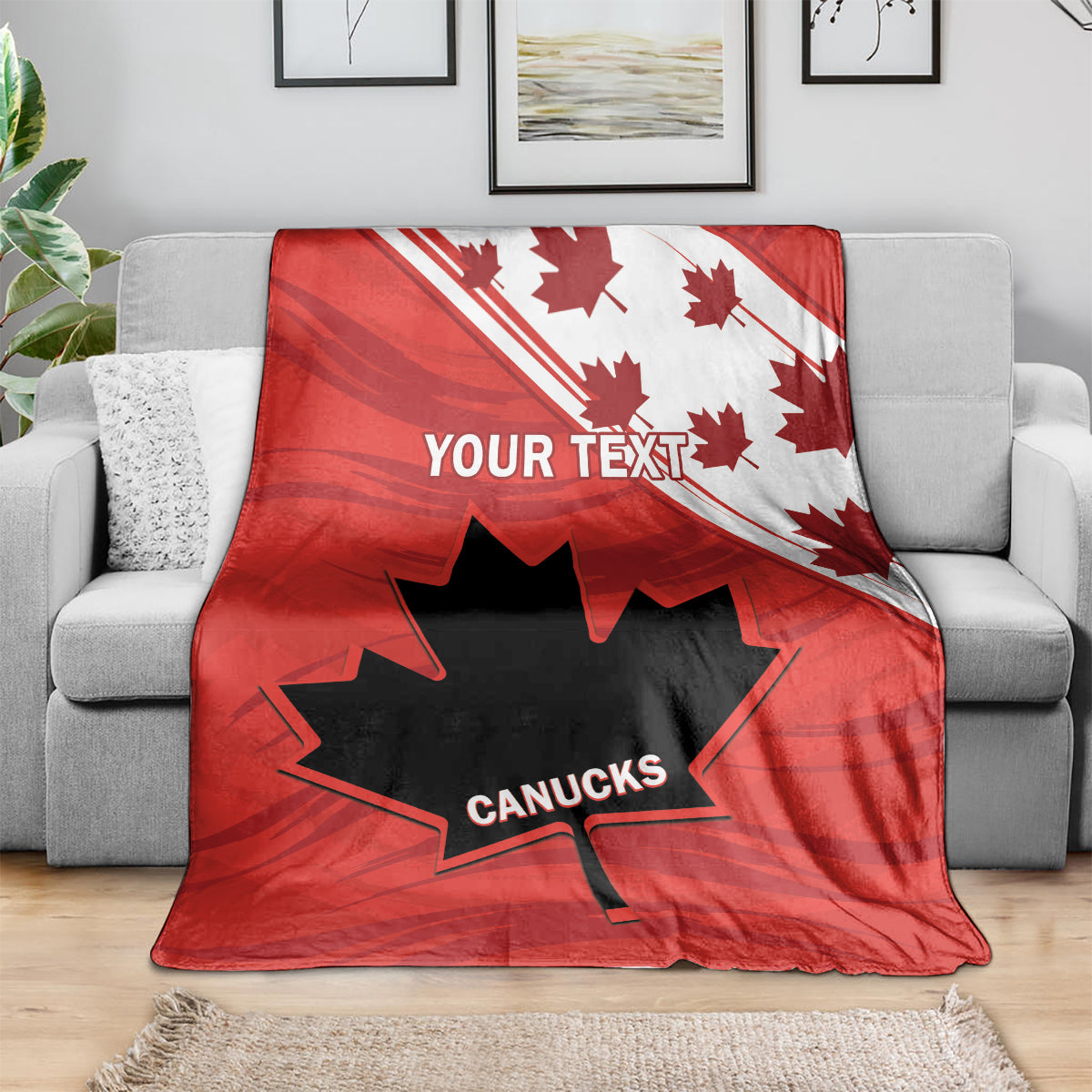 Red Canada rugby blanket with maple leaves and CANUCKS graphic, draped on sofa