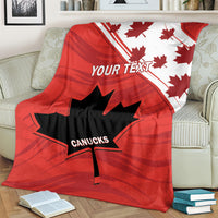 Red blanket with maple leaves, diagonal stripe, and CANUCKS logo, covering armchair