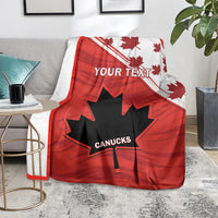 Red Canada blanket with maple leaf border and CANUCKS logo, draped on floor