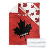 Red Canada blanket with maple leaves and CANUCKS logo, folded with rolled towels