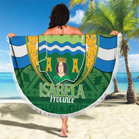Green round beach blanket with white fringe and Isabela Province crest held up outdoors