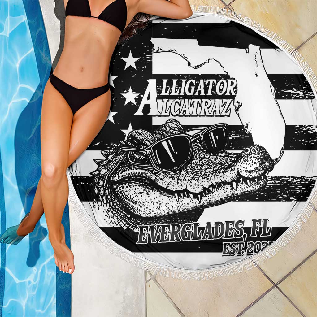 Round fringed beach blanket in black and white with alligator graphic, laid poolside