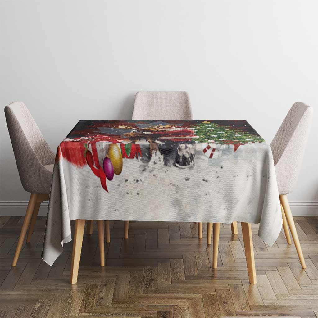 Christmas tablecloth on a square dining table with Santa and moose design, red ornaments on base