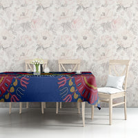 Blue dashiki-pattern tablecloth with red accents on dining table against floral wall