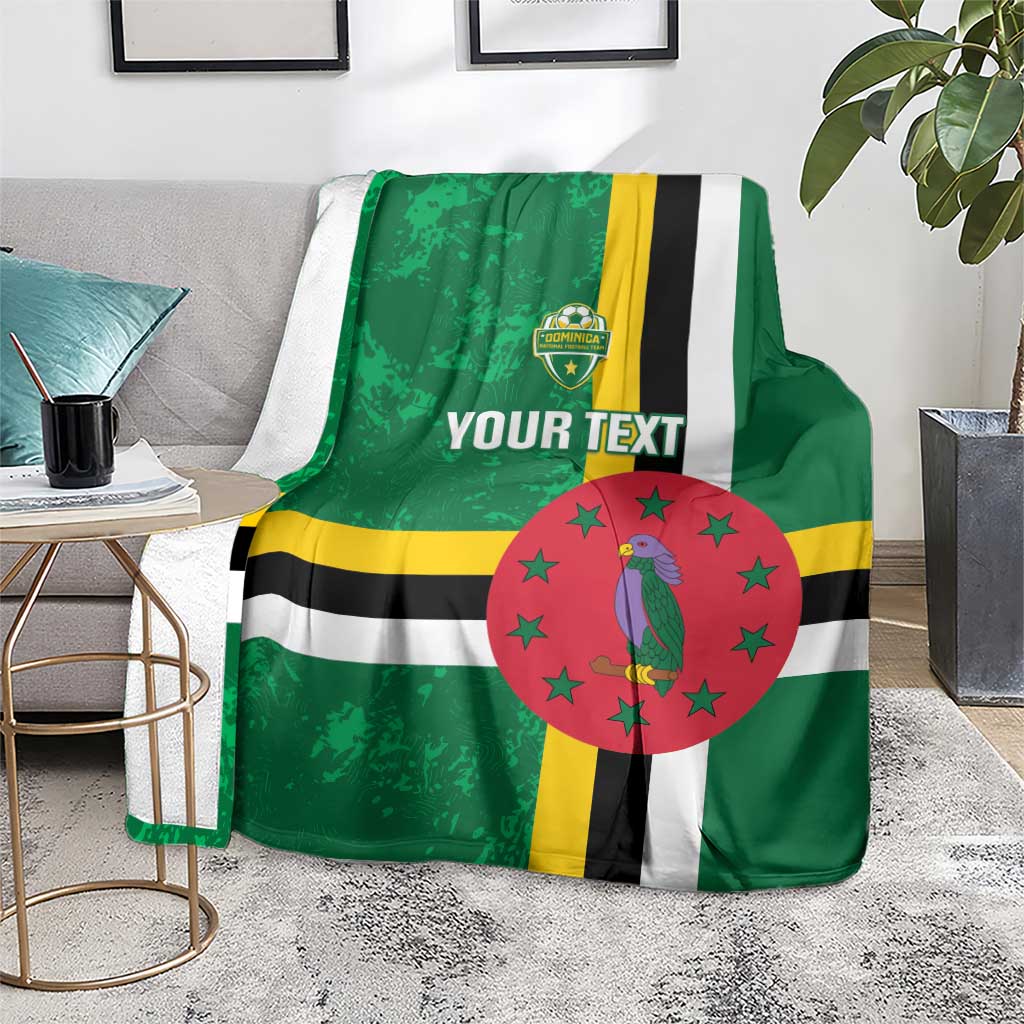 Green football blanket on couch with Dominica flag stripes, bird emblem in red circle, custom text