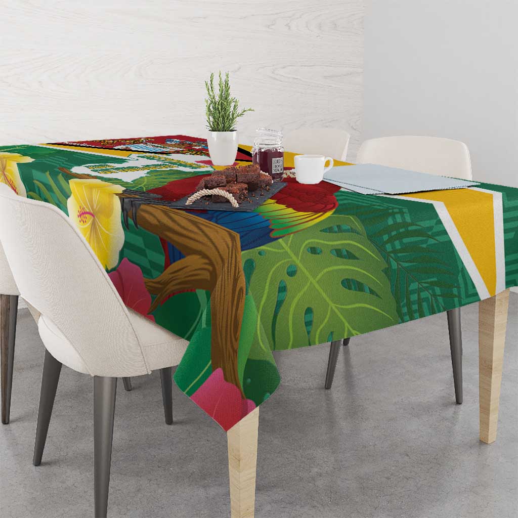 Green tropical tablecloth with yellow trim, scarlet macaw artwork, and leaf print pattern