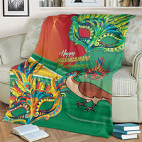 Green Mashramani anniversary blanket with bird and mask graphics, draped over armchair