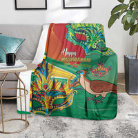 Green Mashramani anniversary blanket with bird and colorful mask artwork, draped on floor