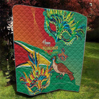 Folded green quilt with red panel, bird figure, and colorful festival mask motif