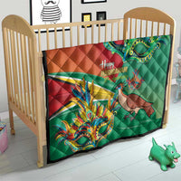 Green and red quilt on crib with colorful bird, dragon mask, and “Happy Mashramani”