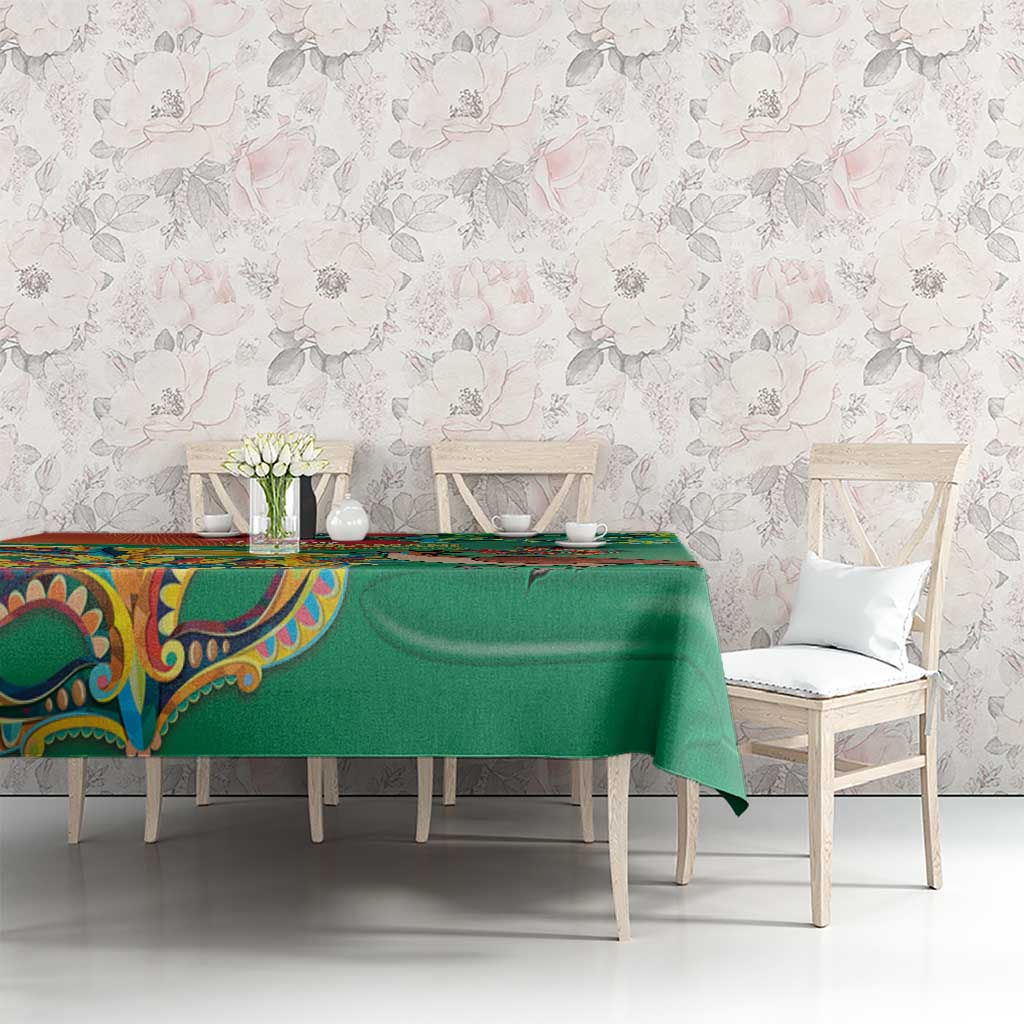 Green tablecloth on a dining table with floral-themed print and colorful detailing