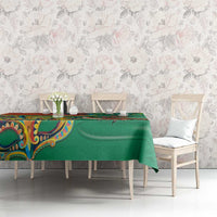 Green tablecloth on a dining table with floral-themed print and colorful detailing