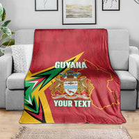 Red Guyana cricket blanket with crest and YOUR TEXT, spread over grey sofa