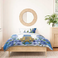 Blue bedding set with cornflower floral print and central crest, styled on a wooden bed
