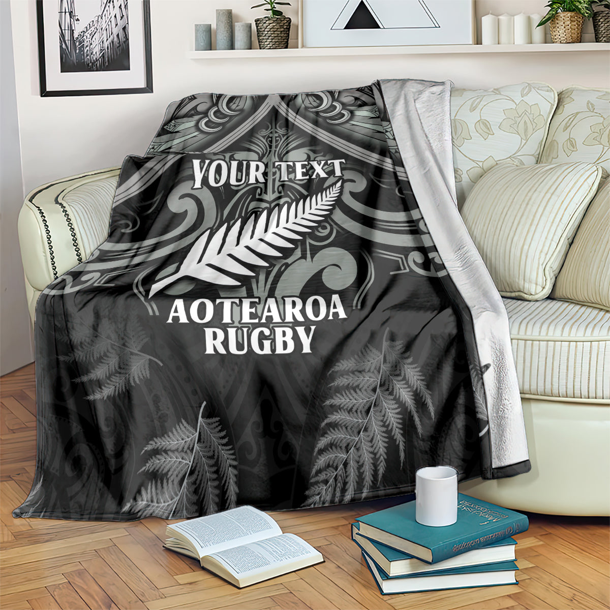 Black rugby blanket with fern design, 'YOUR TEXT' and 'AOTEAROA RUGBY', on a bed