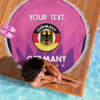 Pink circular beach blanket laid flat with white fringe and Germany football logo