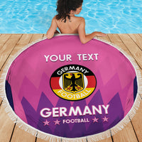 Pink round Germany football beach blanket with white fringe, viewed from behind