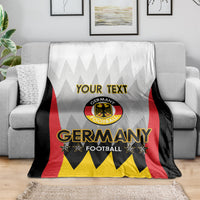 White Germany football blanket with “YOUR TEXT” and Germany crest on couch, red black yellow design