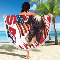 Round white beach blanket with fringe, eagle and rugby graphics, held overhead on sand