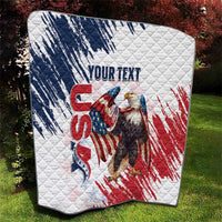 White quilt laid on grass with American flag eagle design and quilted diamond texture.