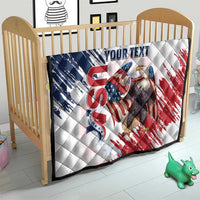 White quilt on wooden crib with American flag eagle graphic and quilted diamond texture.