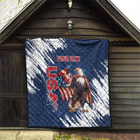 Blue and white quilt hanging outdoors, quilted stitching with eagle graphic and red text