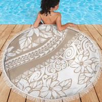 Beige round beach blanket with white tropical print and fringed trim, partially spread