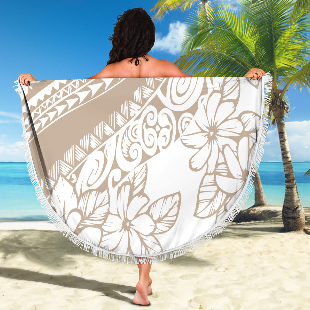 Beige round beach blanket with white hibiscus and geometric motifs, fringed edge held up
