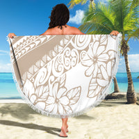 Beige round beach blanket with white hibiscus and geometric motifs, fringed edge held up