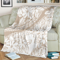Beige and white tropical floral print blanket, draped on a couch cushion